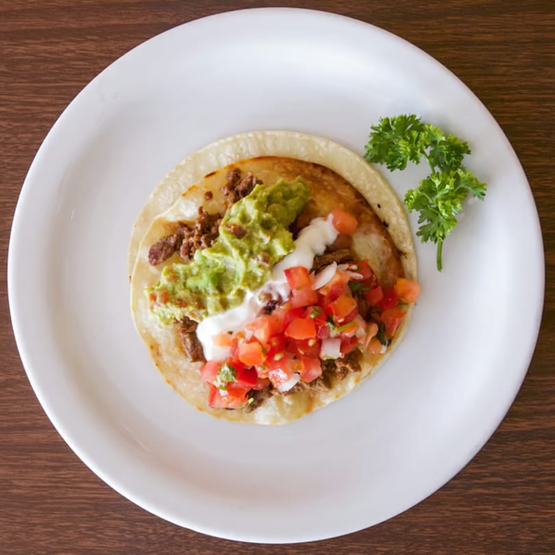 Overhead view of a Taqueria Morena taco with meat, guacamole, sour cream, and pico de gallo.